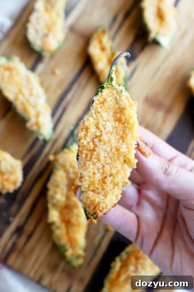 Hand holding an air fryer buffalo jalapeno popper, showing its crispy texture