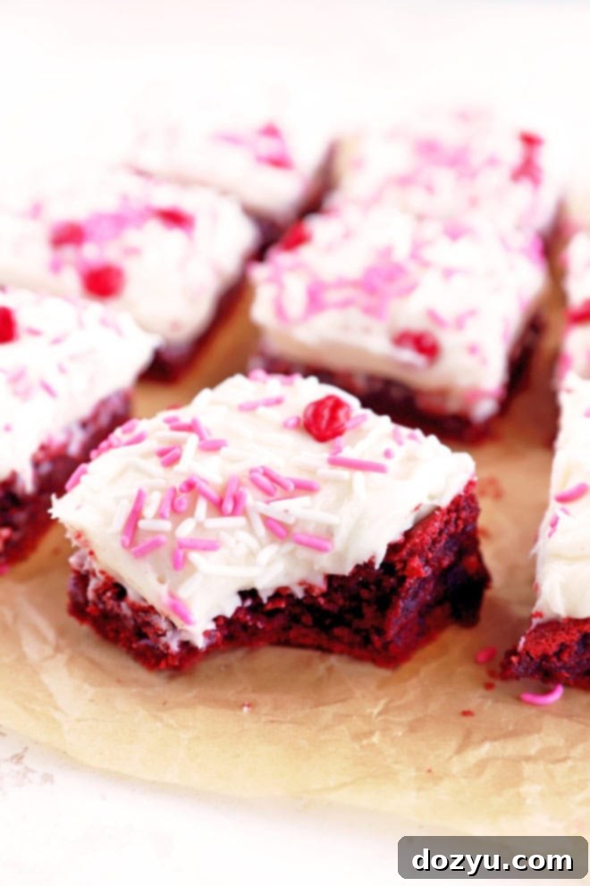 Close-up of a Red Velvet Brownie with a bite taken out, revealing its fudgy interior and vibrant red color beneath the frosting.