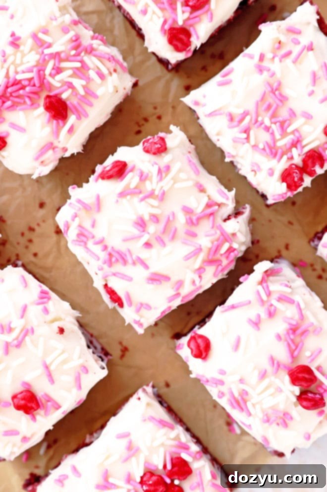 An overhead image showcasing a pan of freshly baked Red Velvet Brownies, some cut into squares, and a few adorned with frosting and sprinkles, perfect for Valentine's Day.