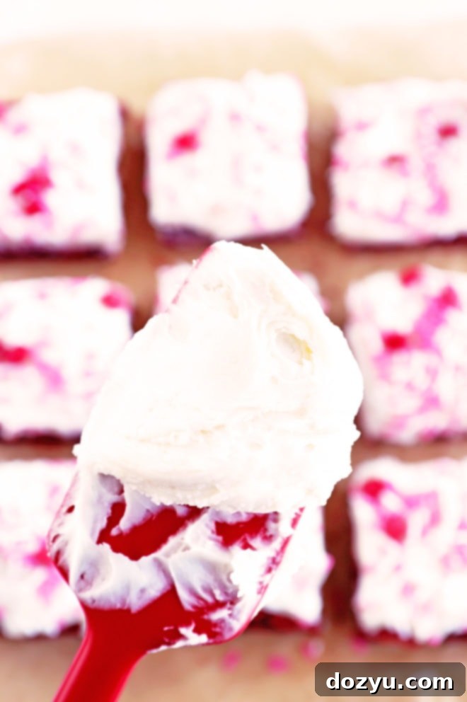 Close-up image of a spatula covered in luscious Champagne Cream Cheese Frosting, ready to be spread onto the brownies.