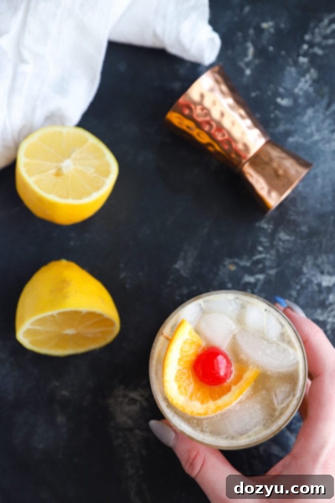 A hand gracefully holding a cocktail glass, filled with a Jameson Whiskey Sour, captured from an overhead perspective.