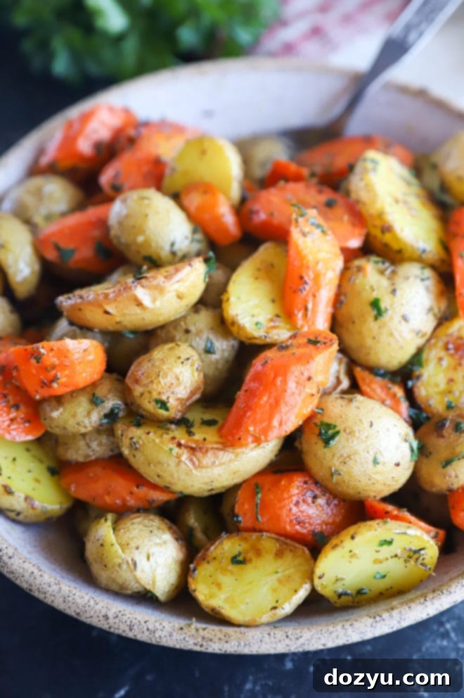 Golden Garlic Butter Roasted Carrots and Potatoes 3 A close-up of garlic butter roasted carrots and potatoes served in a rustic bowl, steam gently rising.