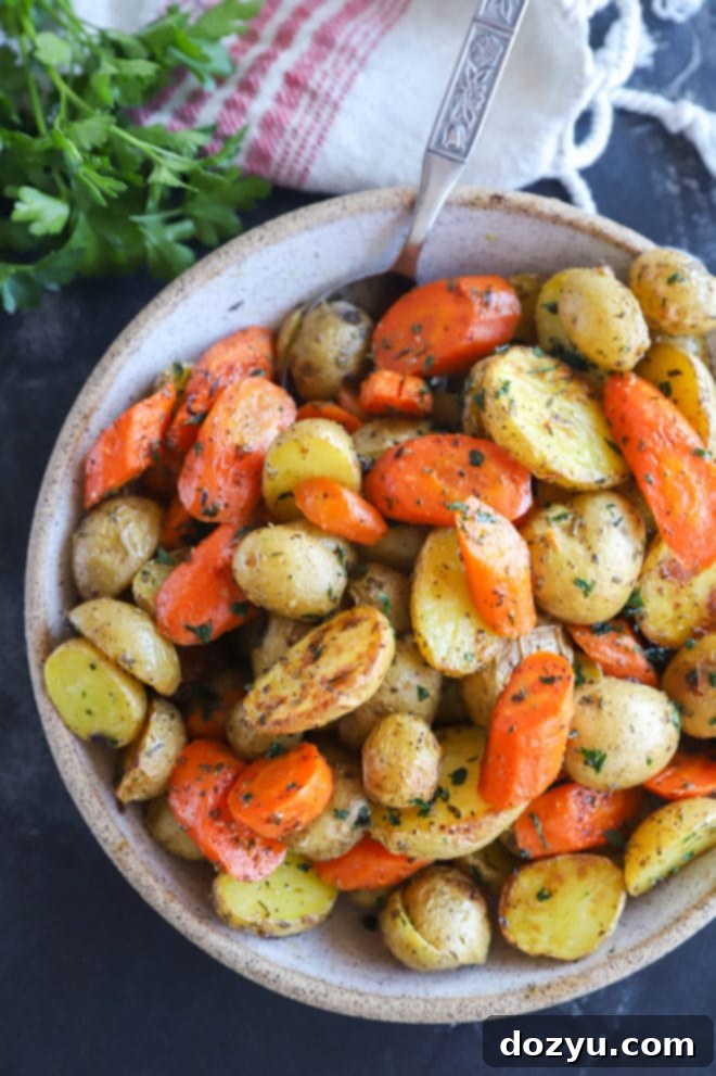 Golden Garlic Butter Roasted Carrots and Potatoes 6 A vibrant image of oven roasted carrots and potatoes in a stylish serving bowl, garnished with fresh green herbs.