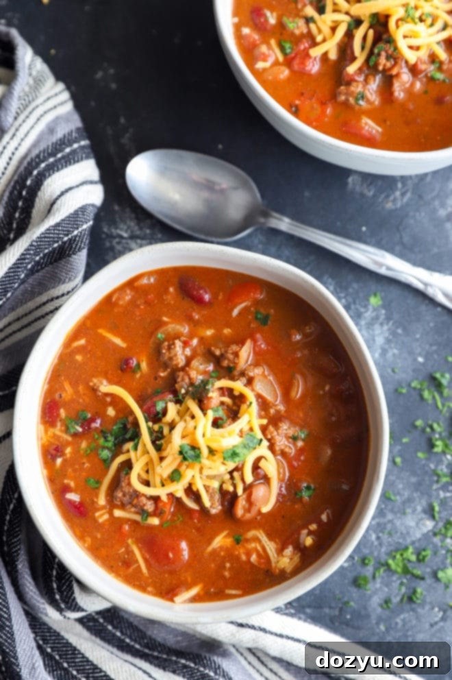An overhead view of three bowls of chipotle chili, each ready for toppings, showcasing the rich, dark color of the soup.