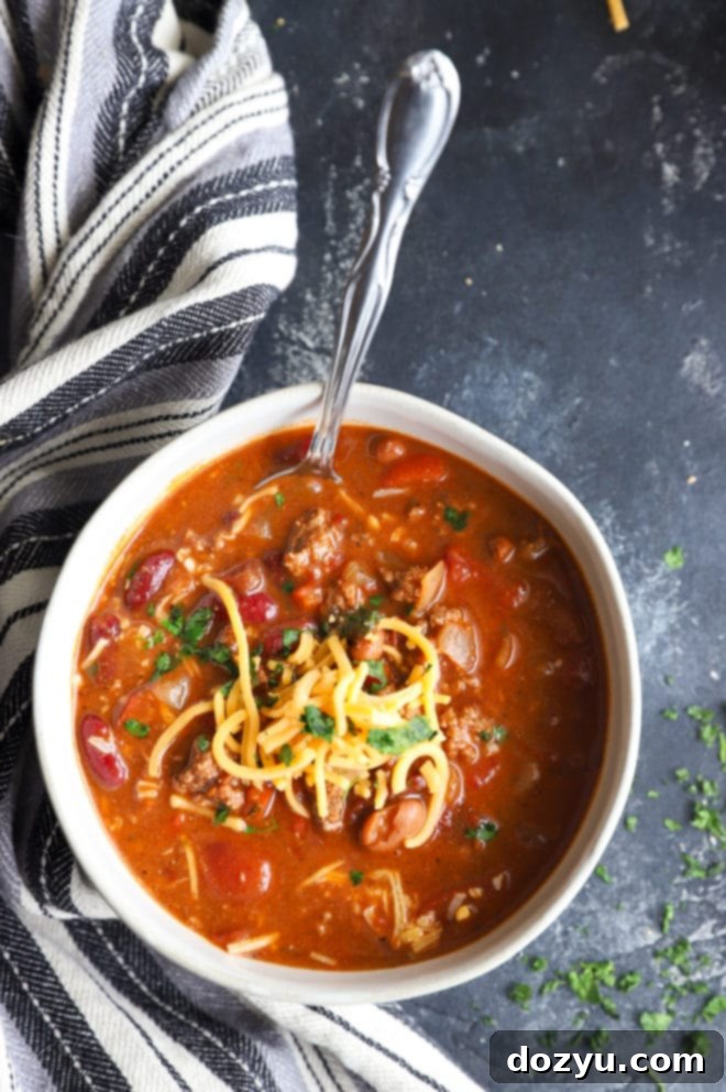 Overhead shot of chipotle chili in a bowl, with a few whole chipotle peppers visible, emphasizing the smoky flavor.