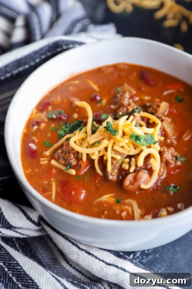 Close-up of shredded cheese melting on top of a serving of chipotle chili in a bowl.