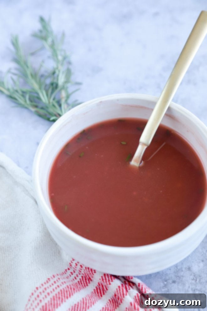 A ceramic bowl filled with homemade red wine sauce, glistening and ready to be drizzled over a main course.