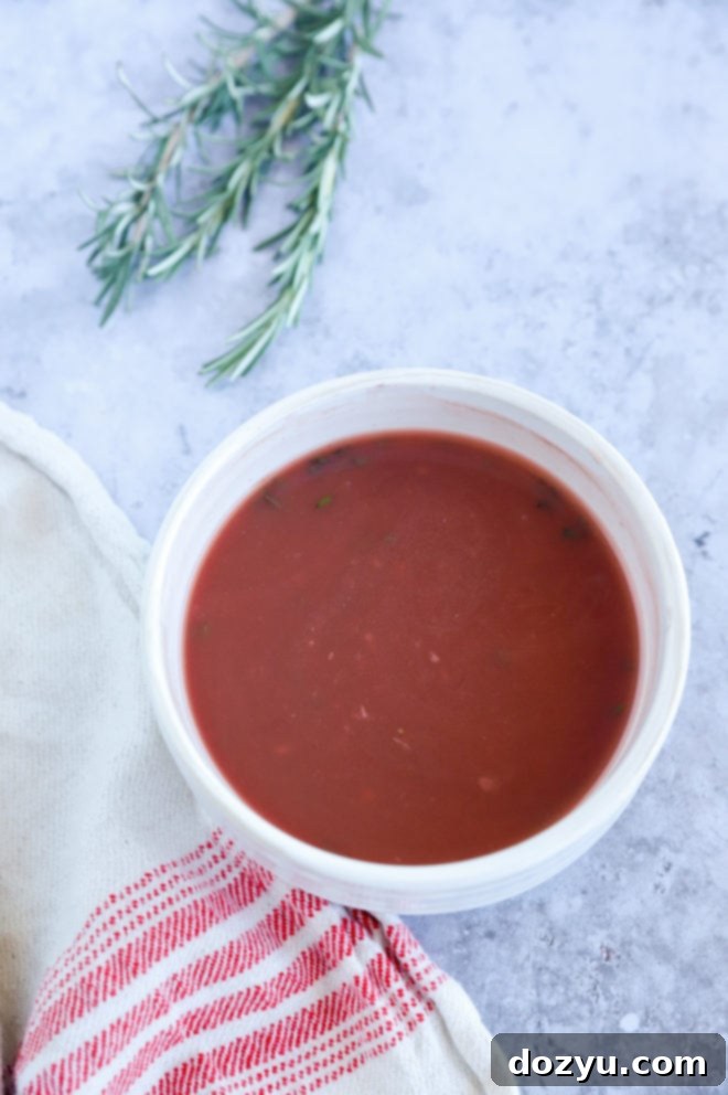 A close-up shot of a bowl of glossy red wine jus, ready to be served as a delicious accompaniment.