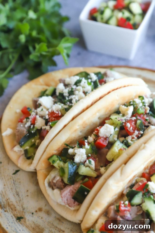 Another close-up side view of a Greek Gyro Lamb Taco on a serving platter, highlighting the texture and fresh toppings.