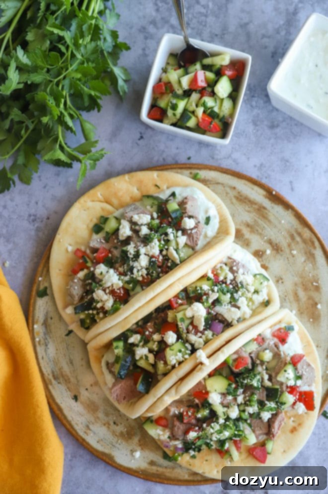 An overhead shot of a platter overflowing with Greek Gyro Lamb Tacos, garnished with fresh ingredients, ready to be served.
