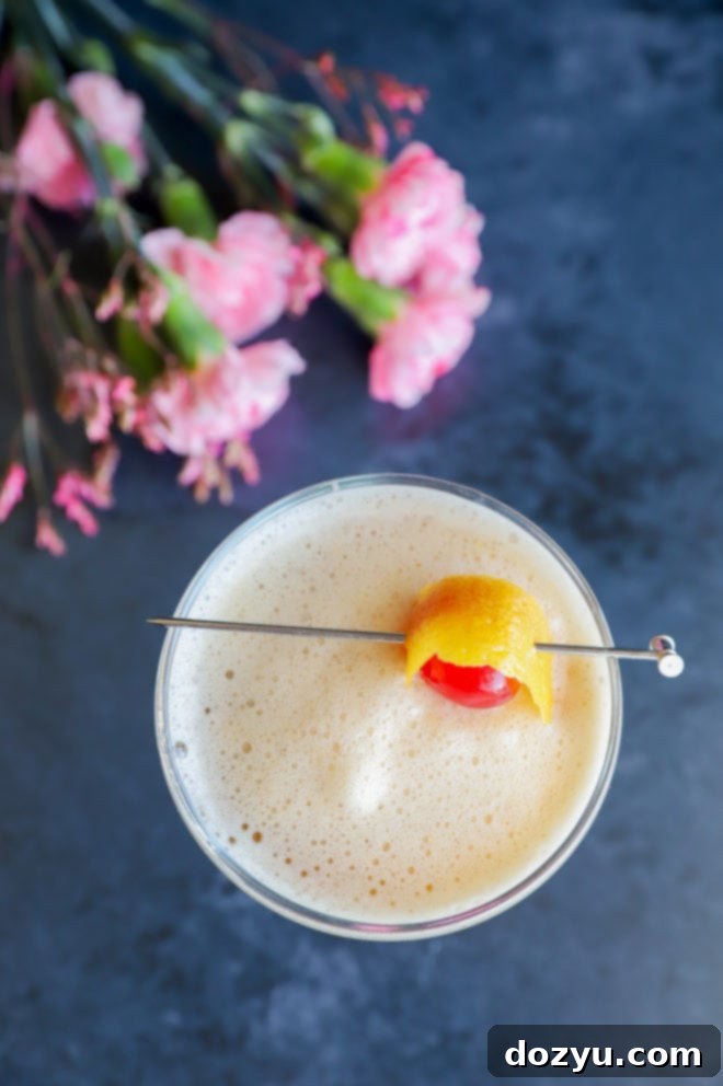 Boston's Spirited Zest 3 Overhead view of a shimmering Boston Sour cocktail in a coupe glass, garnished with a cherry.