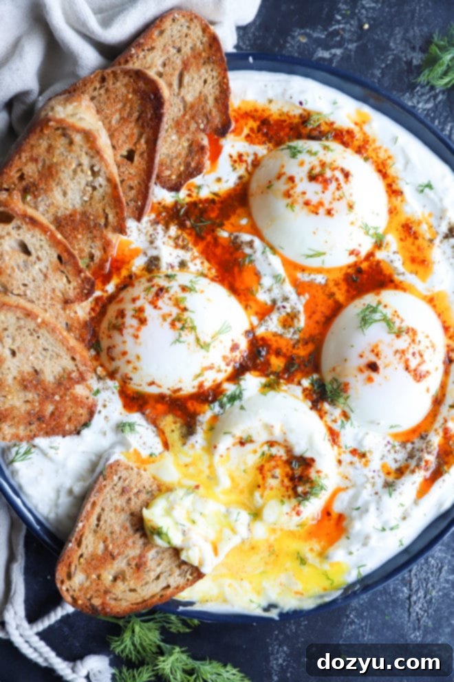 Overhead picture of poached eggs with garlic yogurt, chili butter, and bread, ready to be enjoyed.