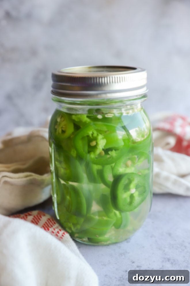 Mezcal infusing with jalapeño and serrano peppers in a mason jar