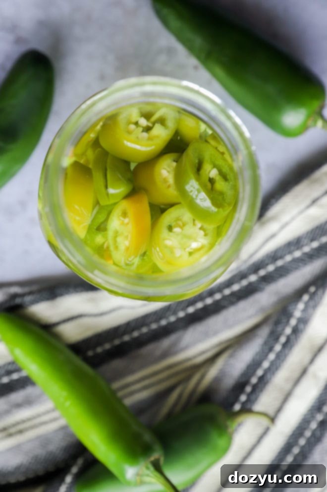 Close-up of a mason jar with mezcal infusing with red and green peppers