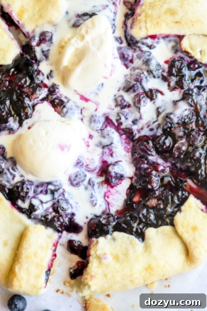 Person eating a slice of blueberry galette with vanilla ice cream