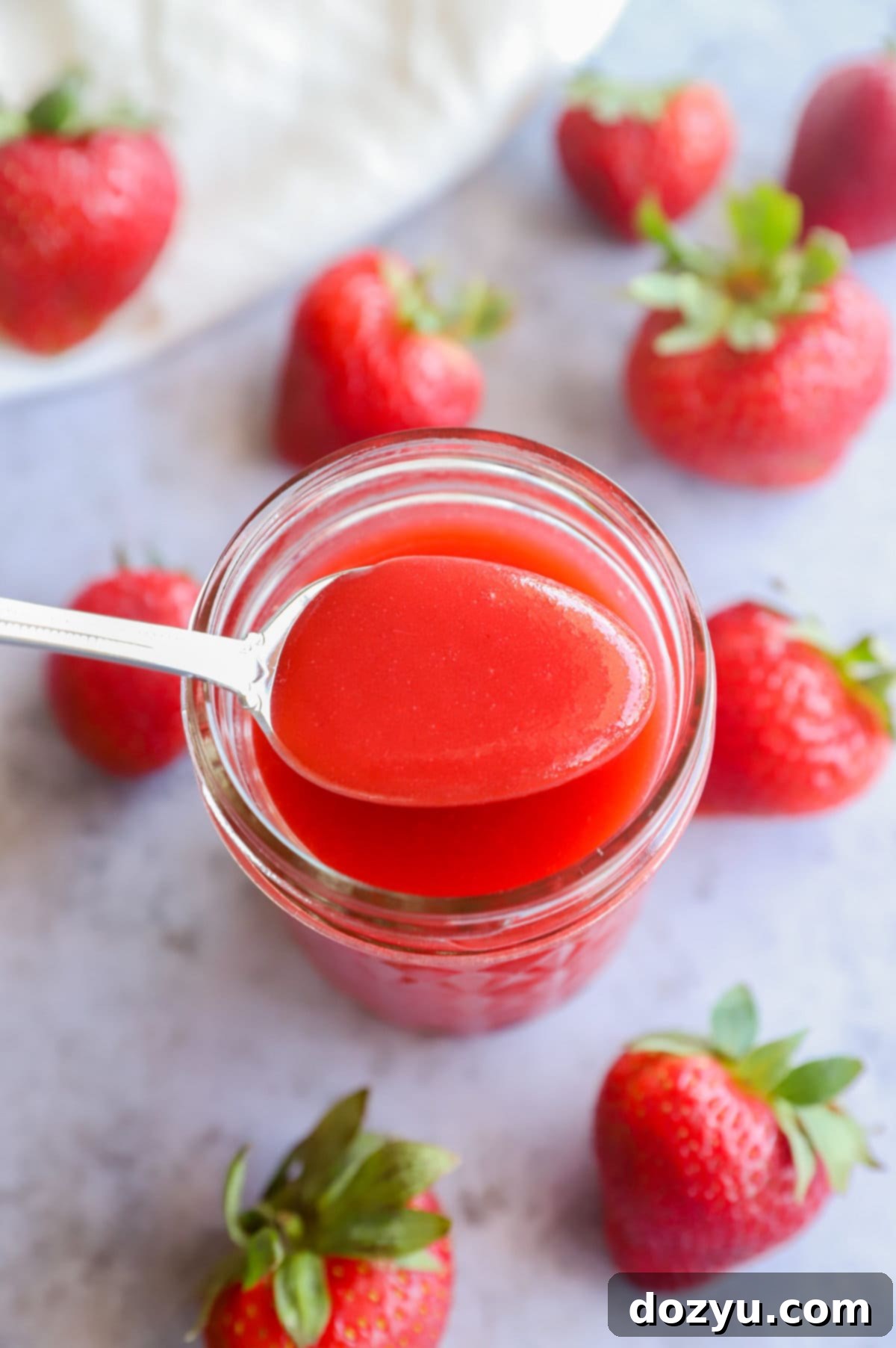 Strawberry coulis on a spoon with strawberries
