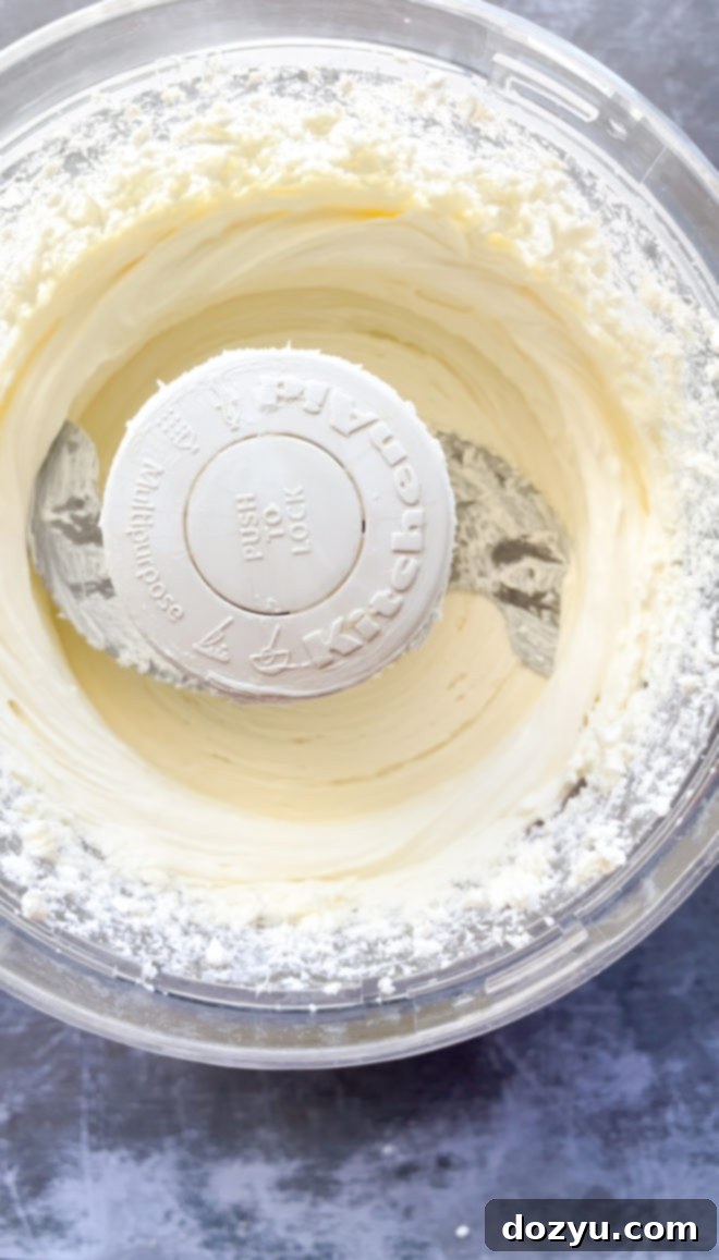 Whipped goat cheese mixture being processed in a food processor, showing its creamy texture
