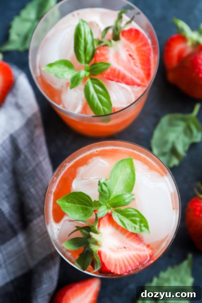 Two glasses of Strawberry Basil Margaritas garnished with fresh basil and strawberries