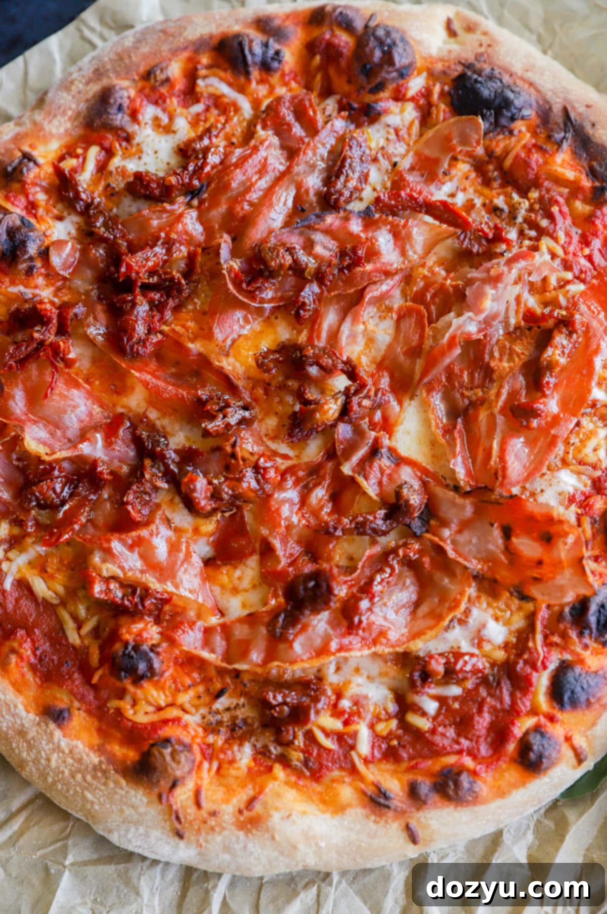 Assembling pizza with sun-dried tomatoes and mozzarella