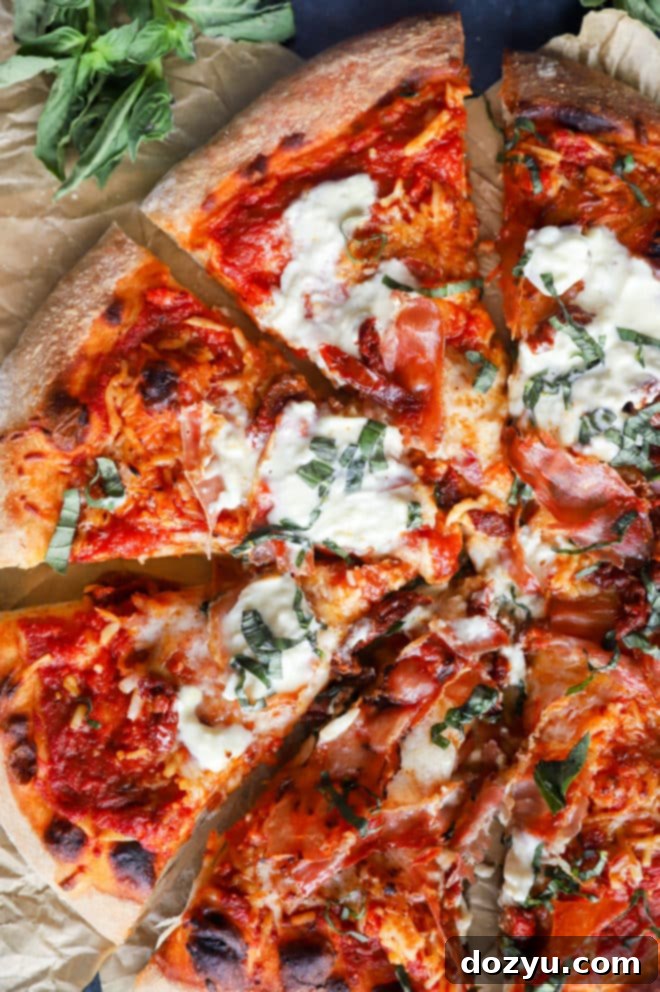 An overhead shot of a freshly grilled Burrata Pizza, topped with bubbling cheese, fresh basil, and cherry tomatoes.