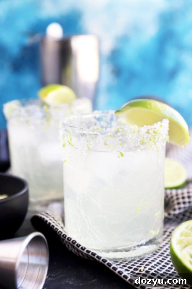 Two glasses of festive Limeade Margaritas, garnished with lime wedges.