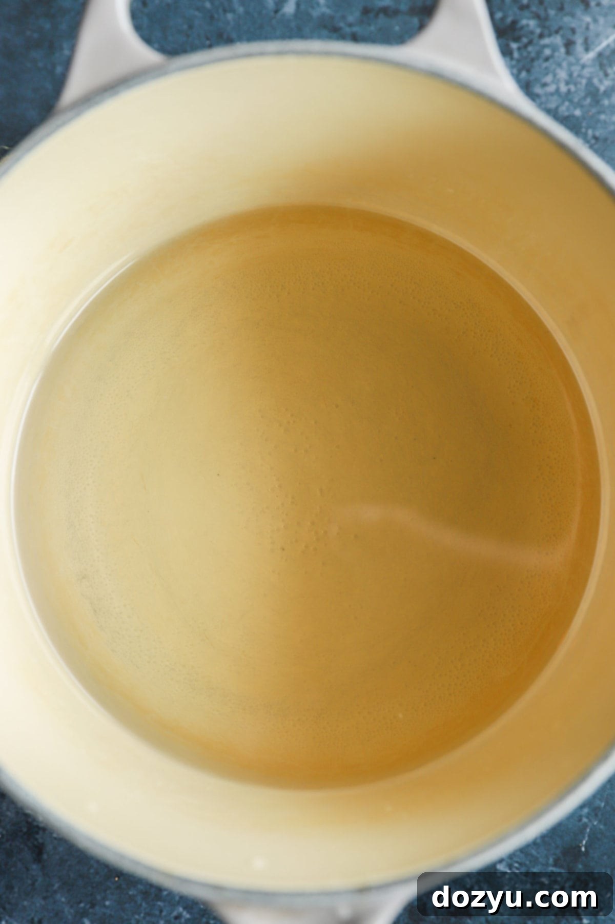 Close-up of a saucepan with water and sugar boiling, beginning the process of making simple syrup.