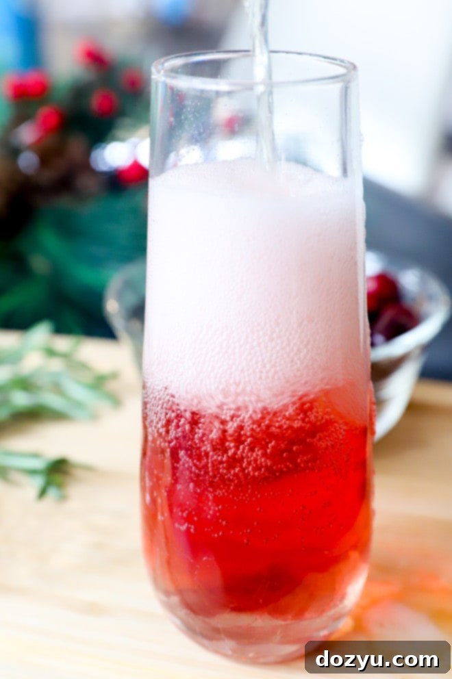 Adding champagne to a champagne flute with cranberry juice and orange liqueur