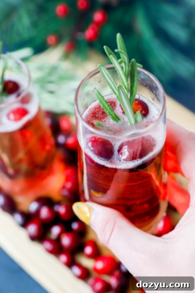 Hand holding champagne flute with cranberry mimosa cocktail