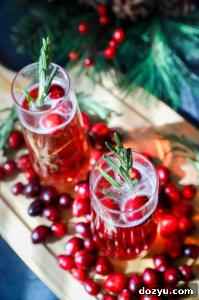 Overhead image of a single cranberry mimosa in a champagne flute, garnished with rosemary and cranberries