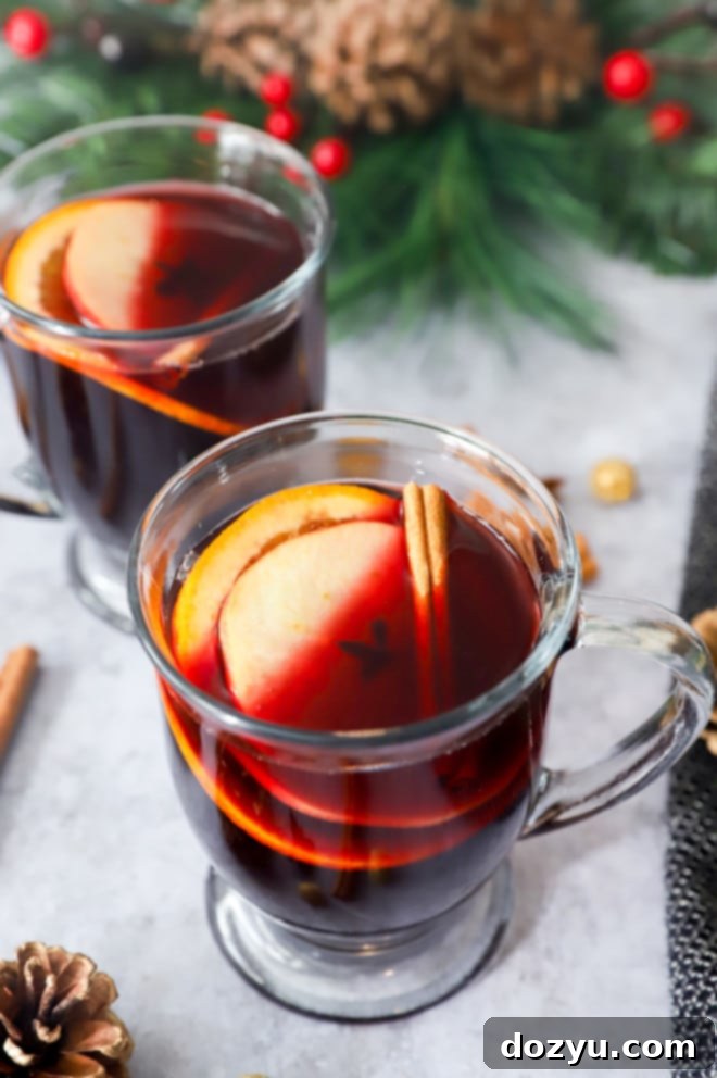 Whole spices, apple, and orange with red wine in mugs