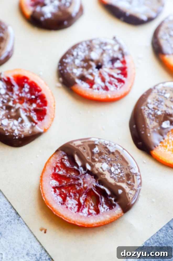 Salted chocolate dipped orange slices laid out on parchment paper