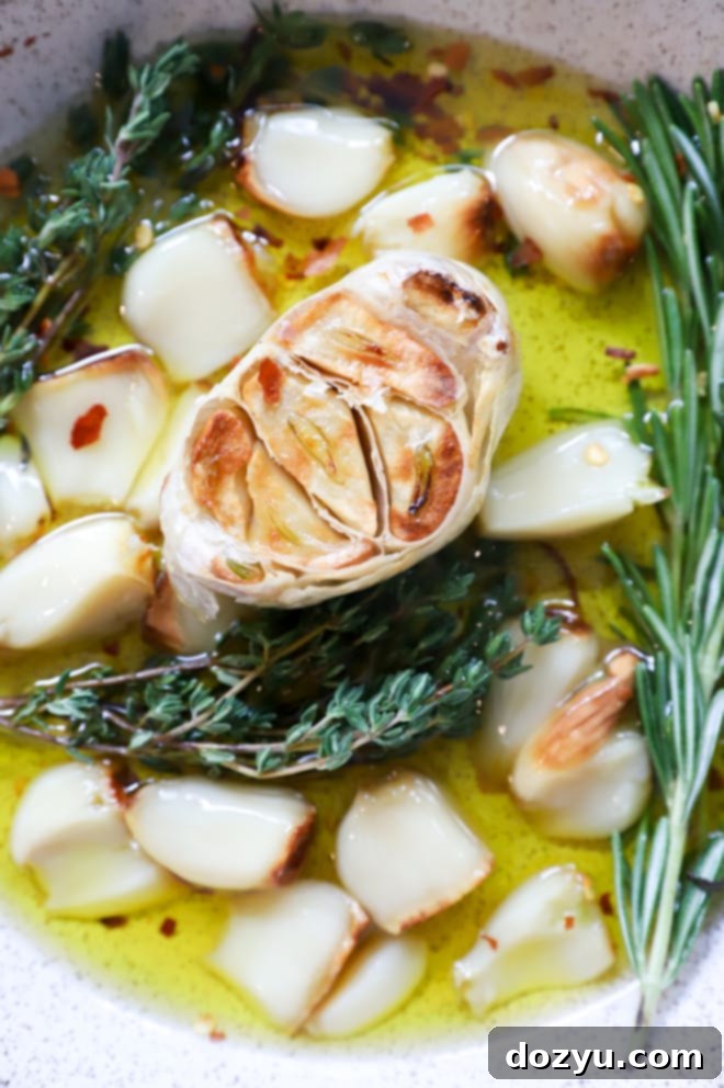 Picture of an air fryer roasted garlic bulb, partially peeled, with several individual cloves next to it.