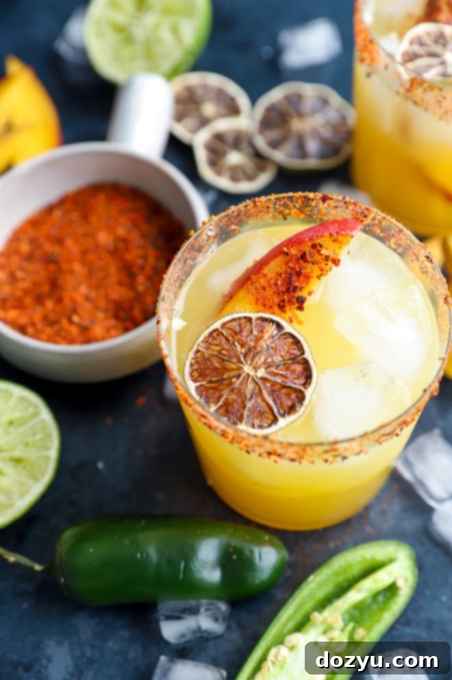 Spicy mango margarita in cocktail glass with fresh jalapeños and mango garnish