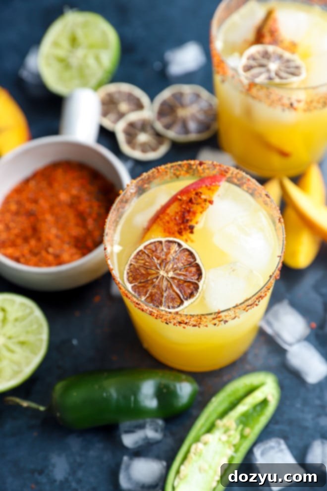 Image of multiple spicy mango margaritas in glasses with lime and mango garnish