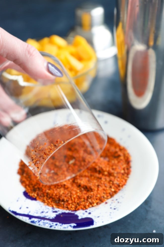 Rimming cocktail glass with Tajin seasoning for a spicy mango margarita