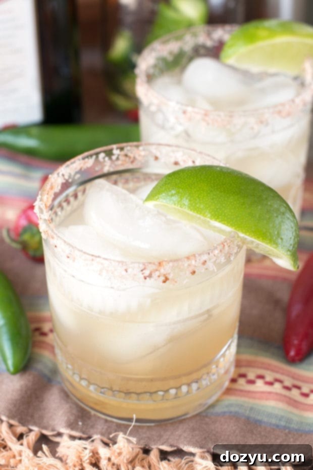 A vibrant Chili Lime Margarita in a salt-rimmed glass, garnished with a lime wedge, offering a spicy and tangy kick.