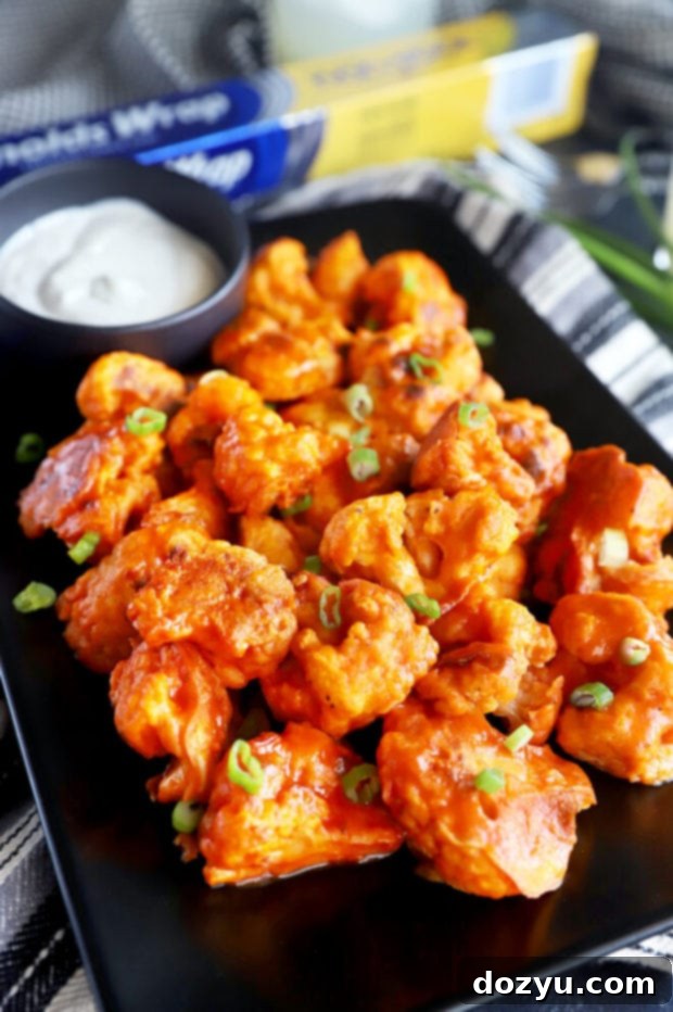 A side photo of beautifully baked crispy buffalo cauliflower florets arranged on a plate, ready to be served.