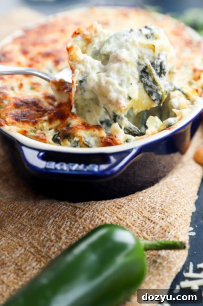 Kickin' Bacon Artichoke Dip 9 Spooning out jalapeño artichoke dip photo, showcasing its creamy texture.