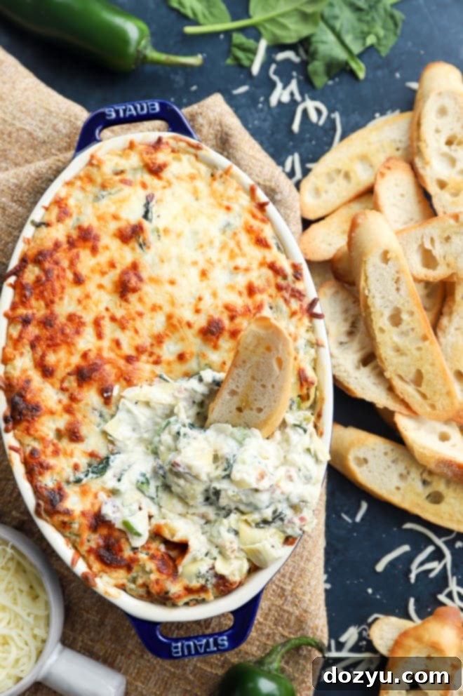 Kickin' Bacon Artichoke Dip 3 Bread dipped in creamy baked dip in baking dish, showing the texture and richness.