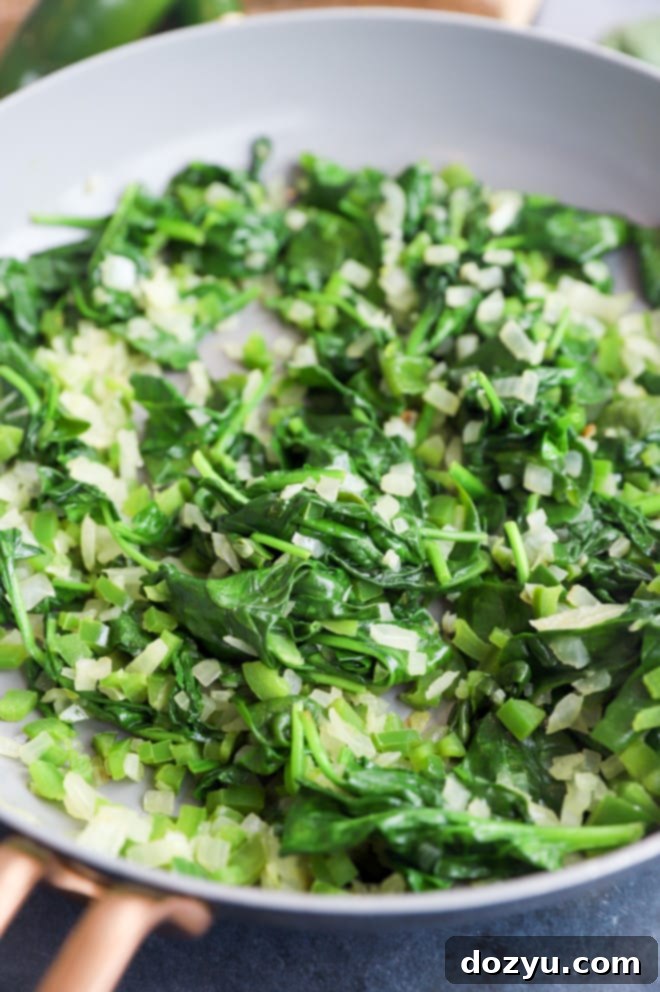 Kickin' Bacon Artichoke Dip 6 Image of cooked spinach with jalapeno and onion, vibrant and fragrant.