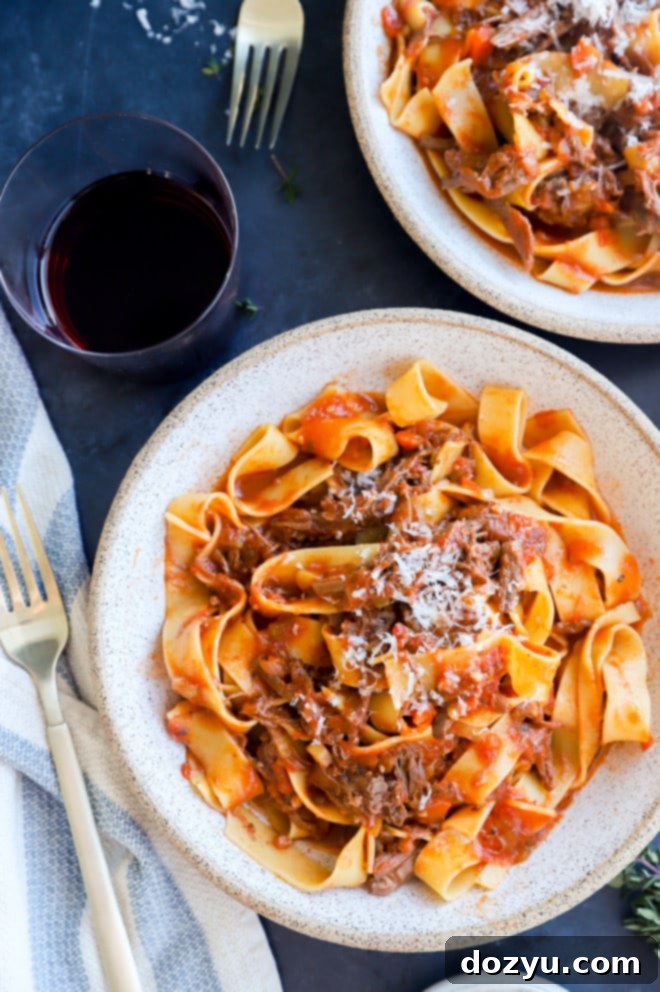 A bowl of Instant Pot Short Rib Ragu with a fork, showing the tender shredded beef