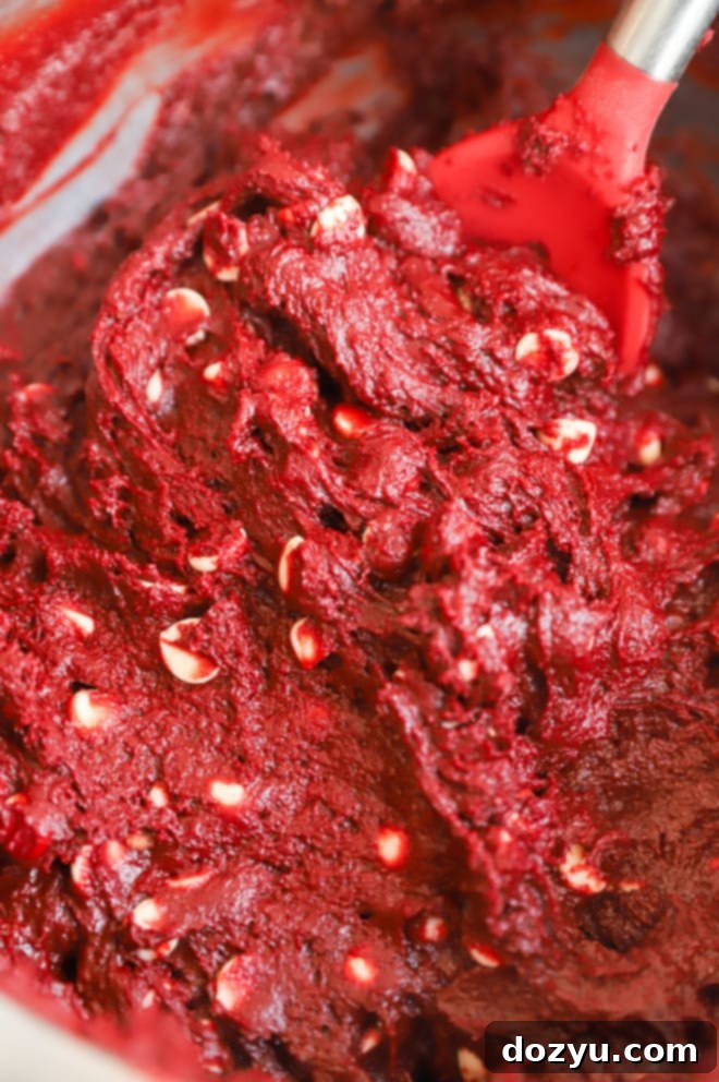 Red velvet muffin batter in a mixing bowl, ready to be scooped.