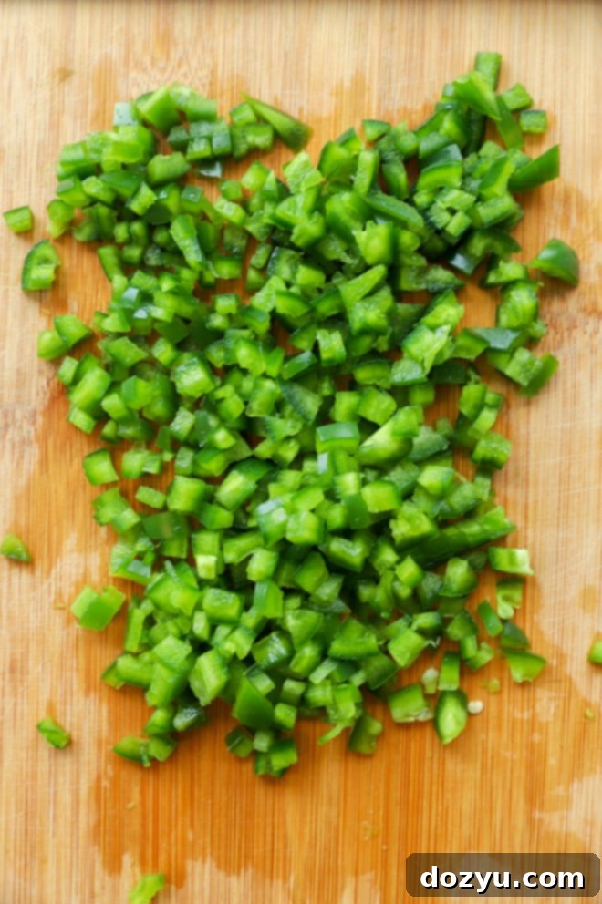 An overhead view of diced jalapeño peppers on a cutting board, ready to be added to a dish.