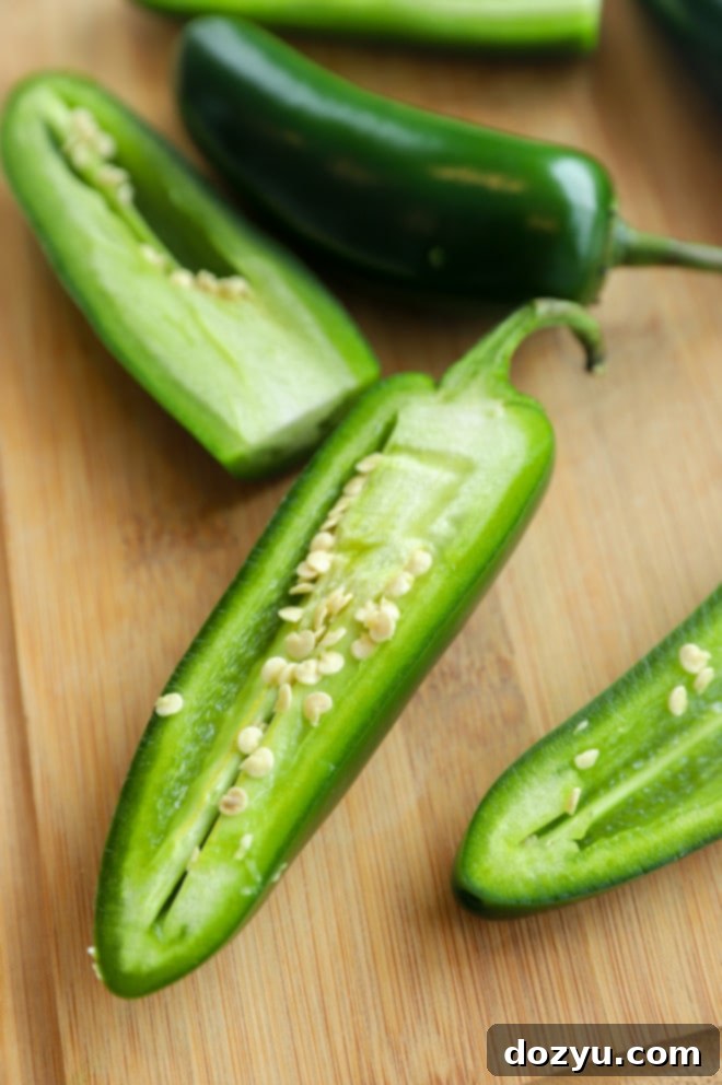 Detailed picture of how to seed a jalapeño pepper on a cutting board with a spoon.