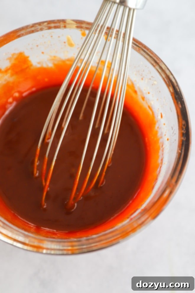 Gochujang Korean chili paste in a small bowl with a whisk, ready for sauce preparation