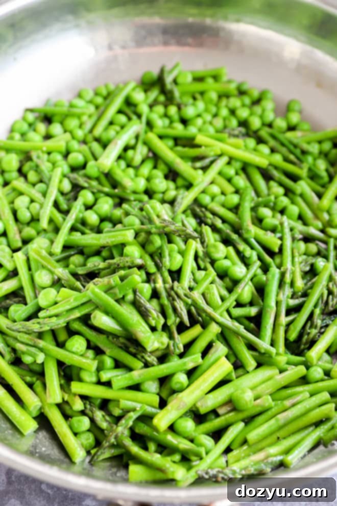 Fresh peas and asparagus gently cooking in a skillet, ready to be added to creamy risotto.