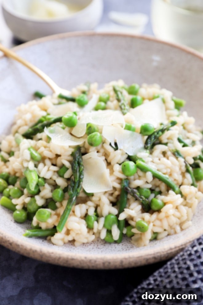 A beautifully presented bowl of creamy spring risotto with asparagus and peas, ready to be enjoyed with a fork.