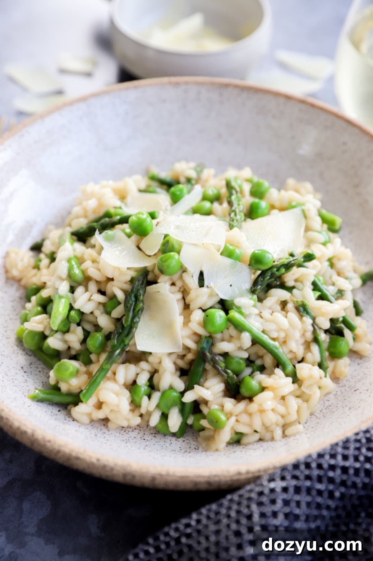 A vibrant bowl of creamy spring risotto with green asparagus spears and peas, perfect for a fresh meal.
