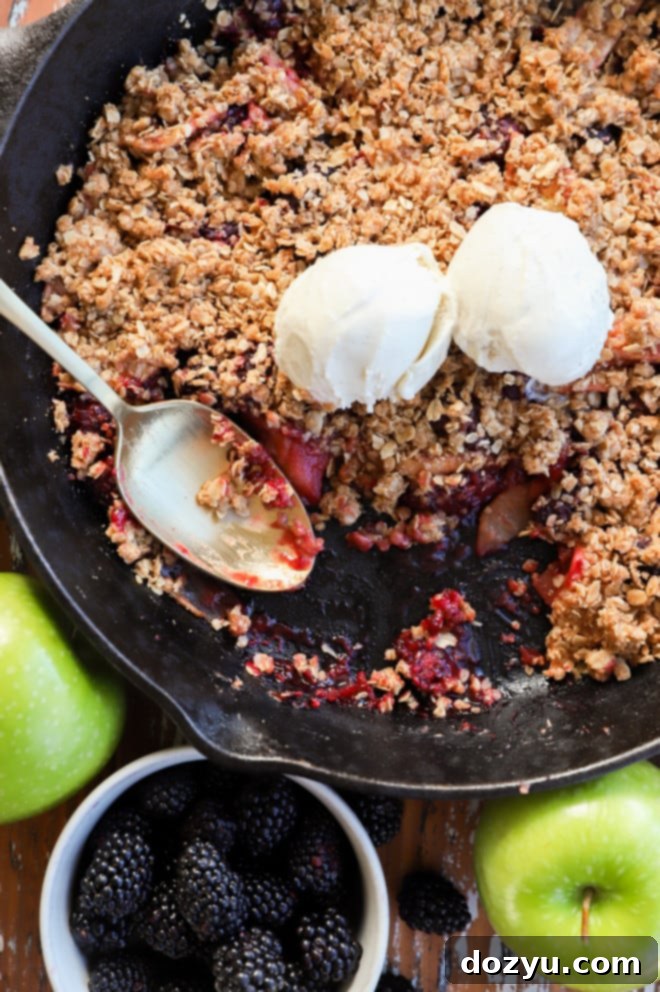 Warm Apple and Blackberry Crumble in a cast iron skillet, ready to serve with a scoop of vanilla ice cream