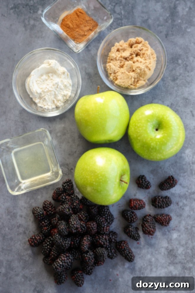 Image displaying various fruit ingredients for apple blackberry crumble, including apples, blackberries, and a lemon